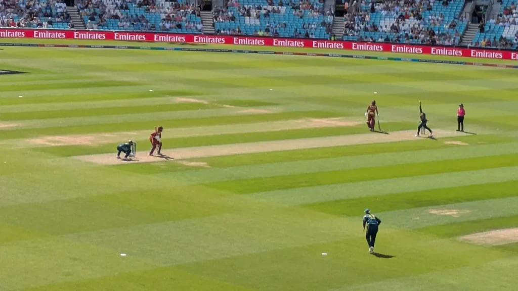 Georgia Wareham bowling for Australia in the Women's T20 World Cup semi-final against the West Indies on 30 June 2026, seen in a wide view of the field with the batters at the crease and fielders spread out. From the semi-final, not the final.