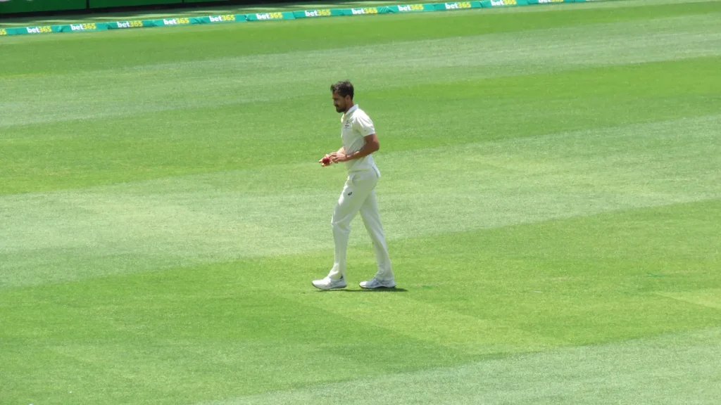 Mitchell Starc in Australia's white Test kit walking across the outfield at Perth Stadium with the red ball in his hands during the first Test against the West Indies, photographed on 2 December 2022. From the 2022 Test, not the 2026 match in Mackay.